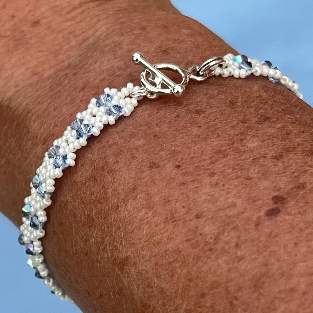 Bracelet Clématite artisanal porté au poignet, cristaux Swarovski bleu ciel