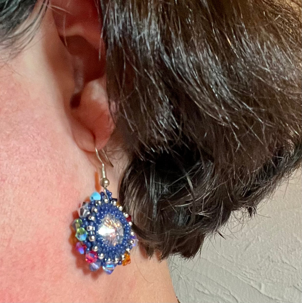 Détail des boucles d'oreilles Iris portée artisanales, perles Miyuki 1mm et cristaux Swarovski multicolores